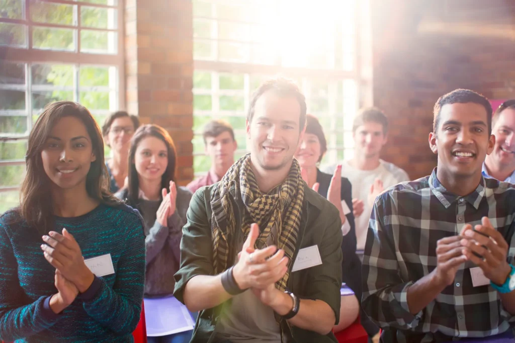 Participants applaudissant lors d'une conférence ensoleillée