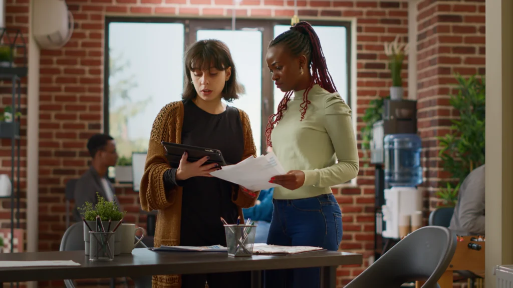 Deux collègues consultent tablette et documents au bureau