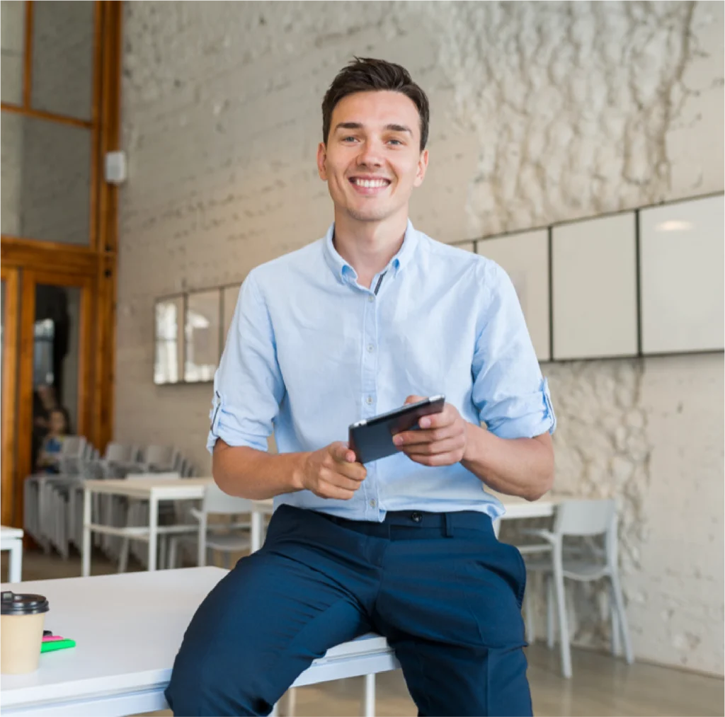 Jeune homme souriant utilisant smartphone au bureau