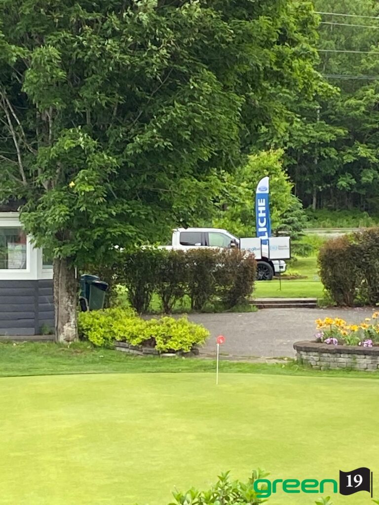 Green de golf avec drapeau et camion blanc