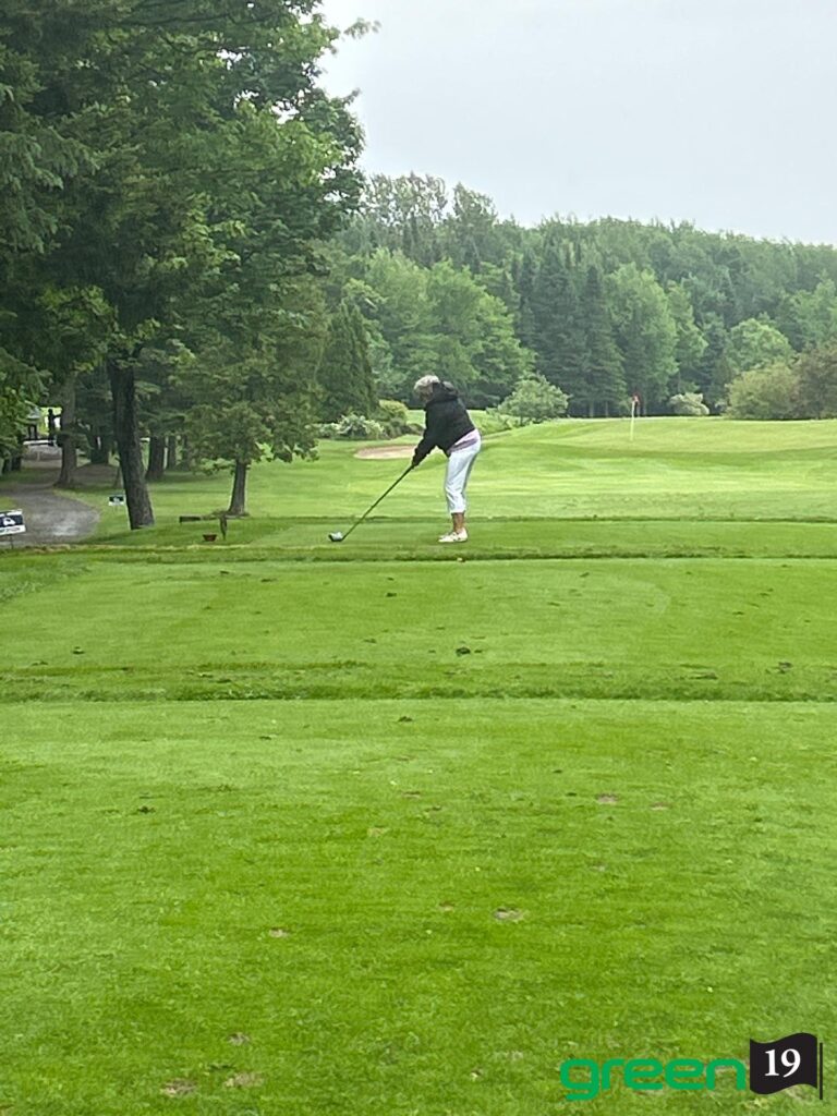 Joueuse de golf au départ sur fairway verdoyant
