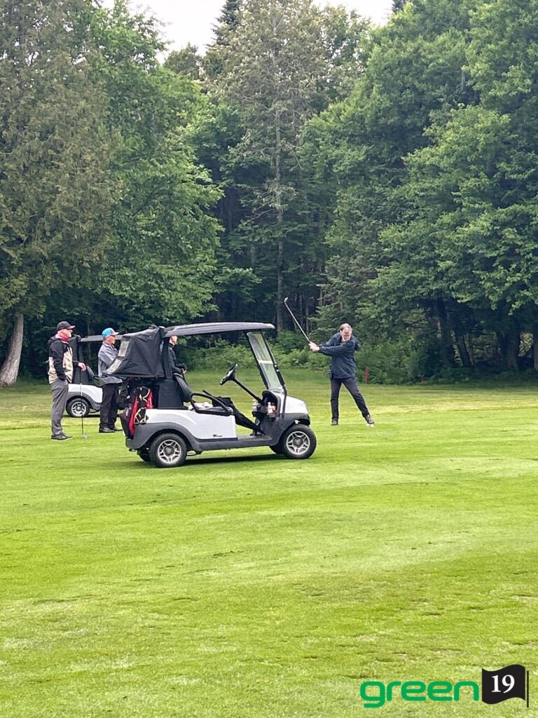 Golfeur frappant la balle près d'une voiturette