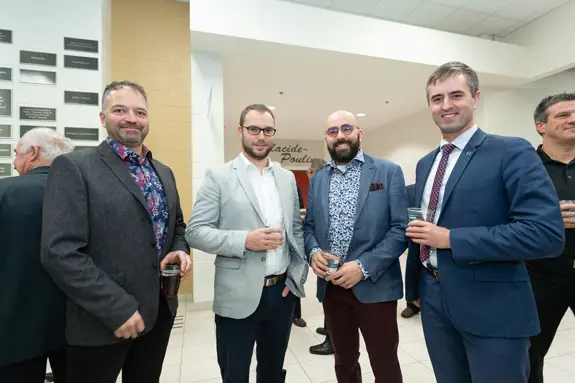 Quatre hommes en costume lors d’un événement professionnel