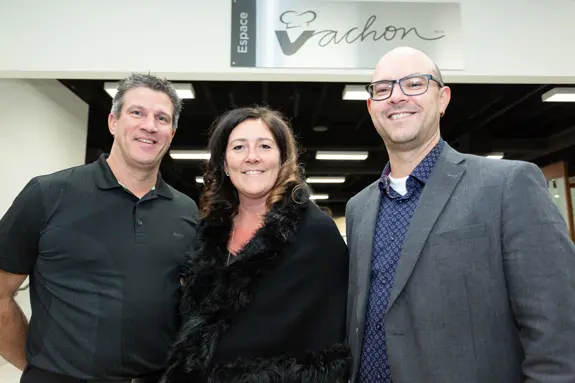 Trois personnes souriantes devant l’enseigne Espace Vachon