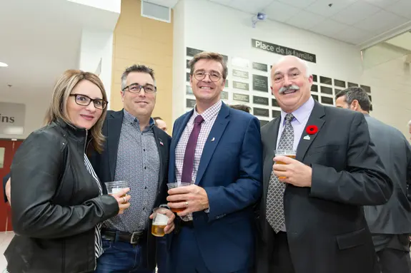 Quatre adultes souriants lors d’une réception intérieure