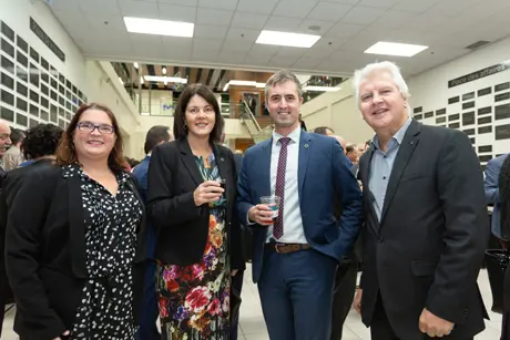 Quatre adultes souriants lors d’un événement professionnel
