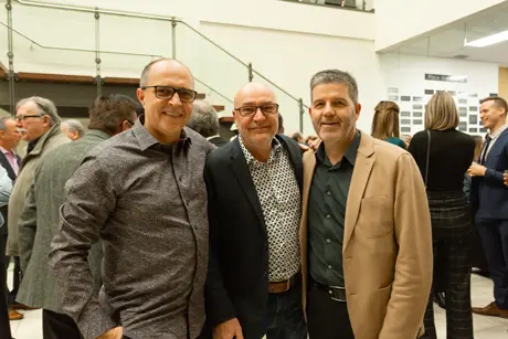 Trois hommes posant lors d’un événement intérieur