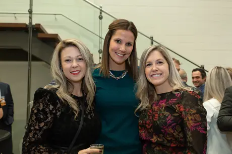 Trois femmes souriantes lors d’un événement intérieur