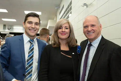 Trois personnes souriantes lors d’un événement intérieur