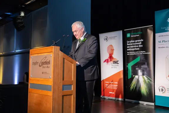 Homme en costume prononçant un discours sur scène