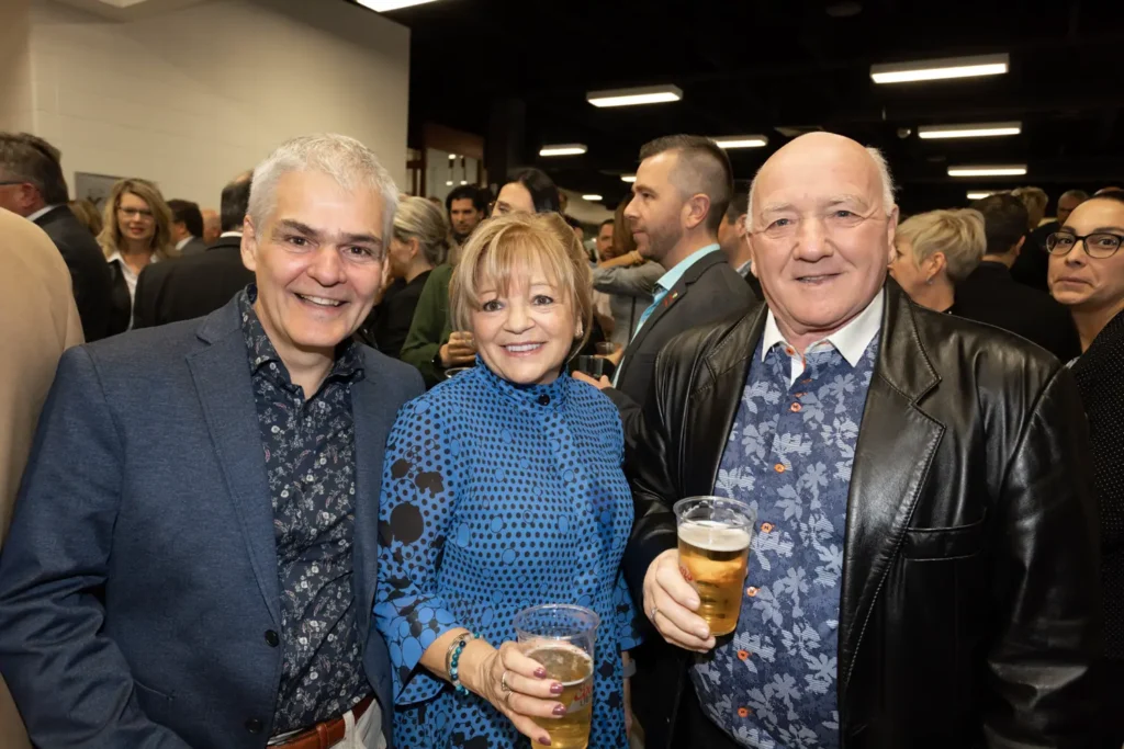 Trois adultes souriants lors d’un événement avec bières