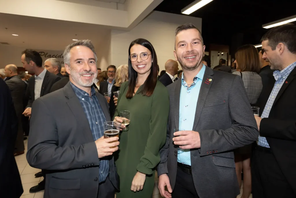 Trois adultes souriants lors d’un cocktail professionnel