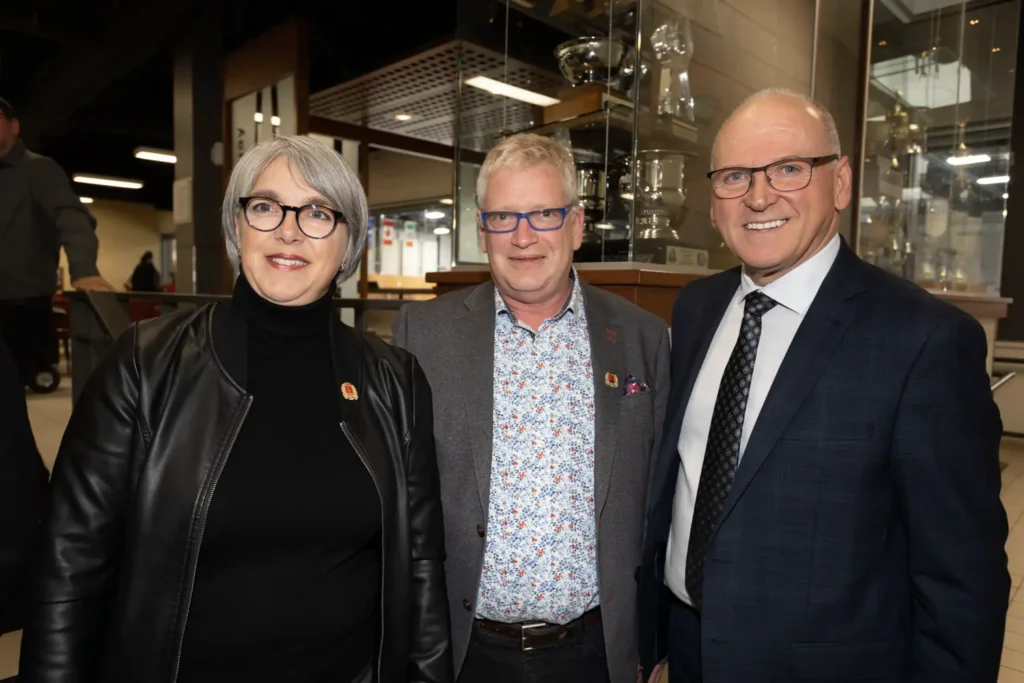 Trois adultes souriants lors d’un événement intérieur