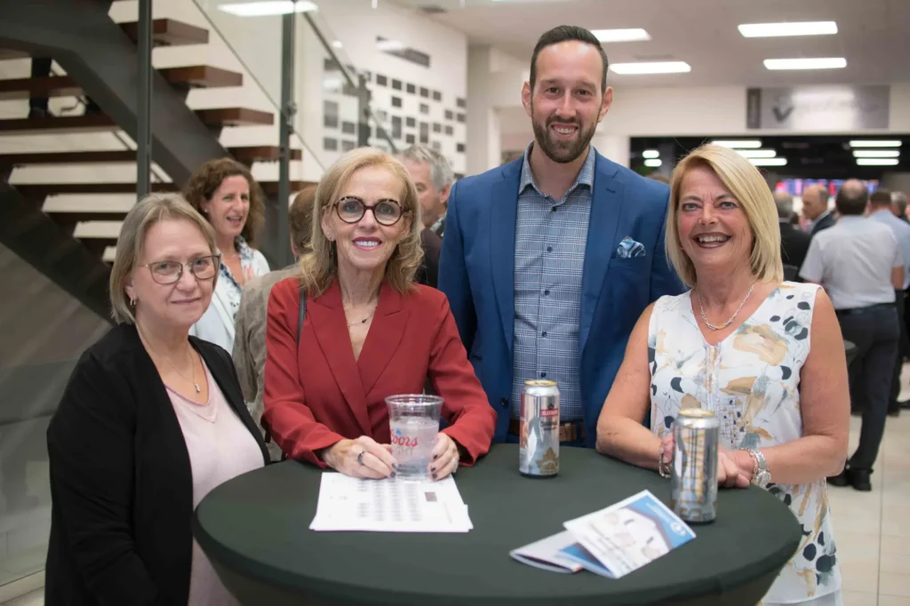 Quatre adultes souriants lors d’un événement professionnel