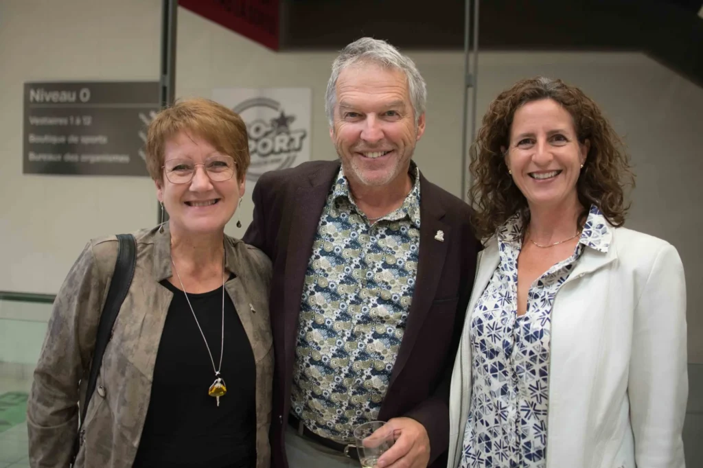 Trois adultes souriants lors d’un événement intérieur