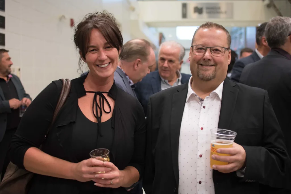 Deux adultes souriants lors d’un événement intérieur