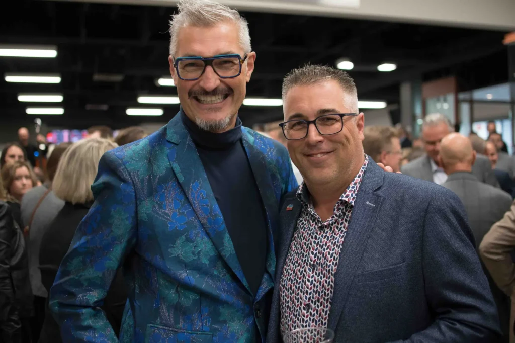 Deux hommes souriants lors d’un événement en intérieur