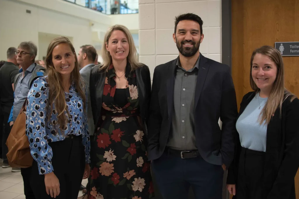 Quatre professionnels souriants lors d’un événement intérieur