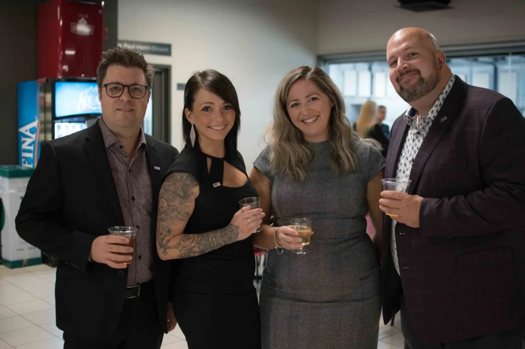 Quatre adultes souriants lors d’un événement professionnel