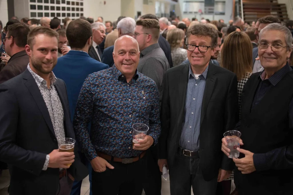 Quatre hommes souriants lors d’un événement professionnel