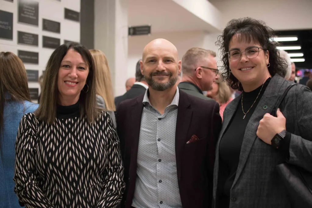 Trois adultes souriants lors d’un événement professionnel