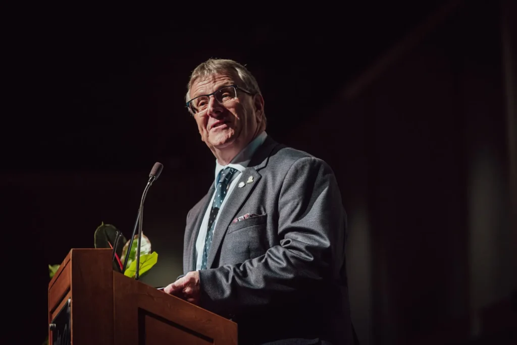 Homme en costume prononçant un discours au pupitre
