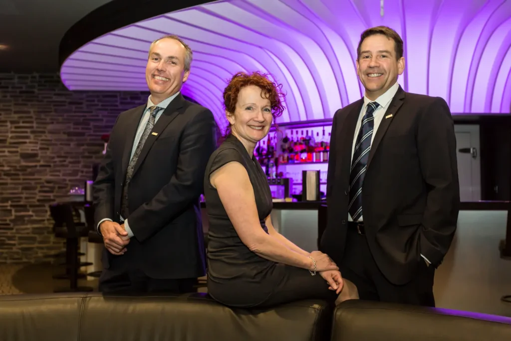Trois professionnels souriants dans un bar moderne