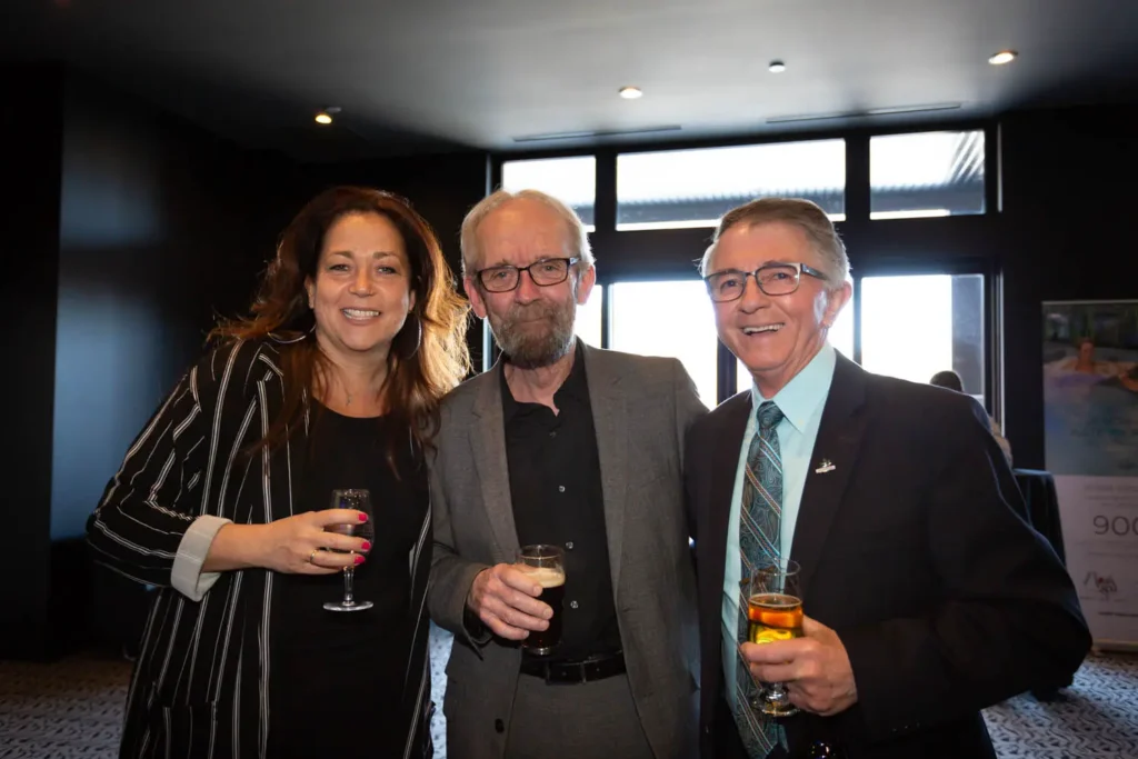 Trois adultes souriants avec verres lors d’un événement