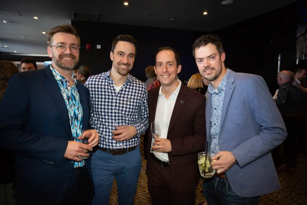 Quatre hommes souriants lors d’un événement professionnel