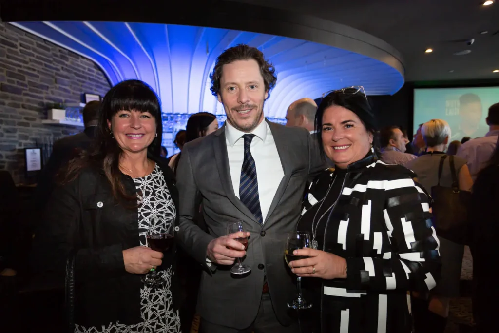 Trois personnes souriantes lors d’un cocktail professionnel
