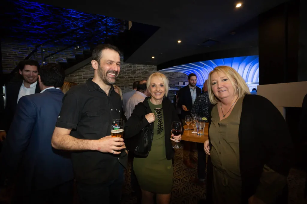 Trois adultes souriants lors d'une soirée conviviale