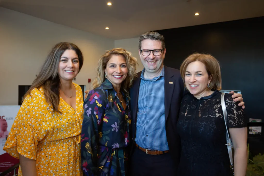 Quatre adultes souriants lors d’un événement intérieur