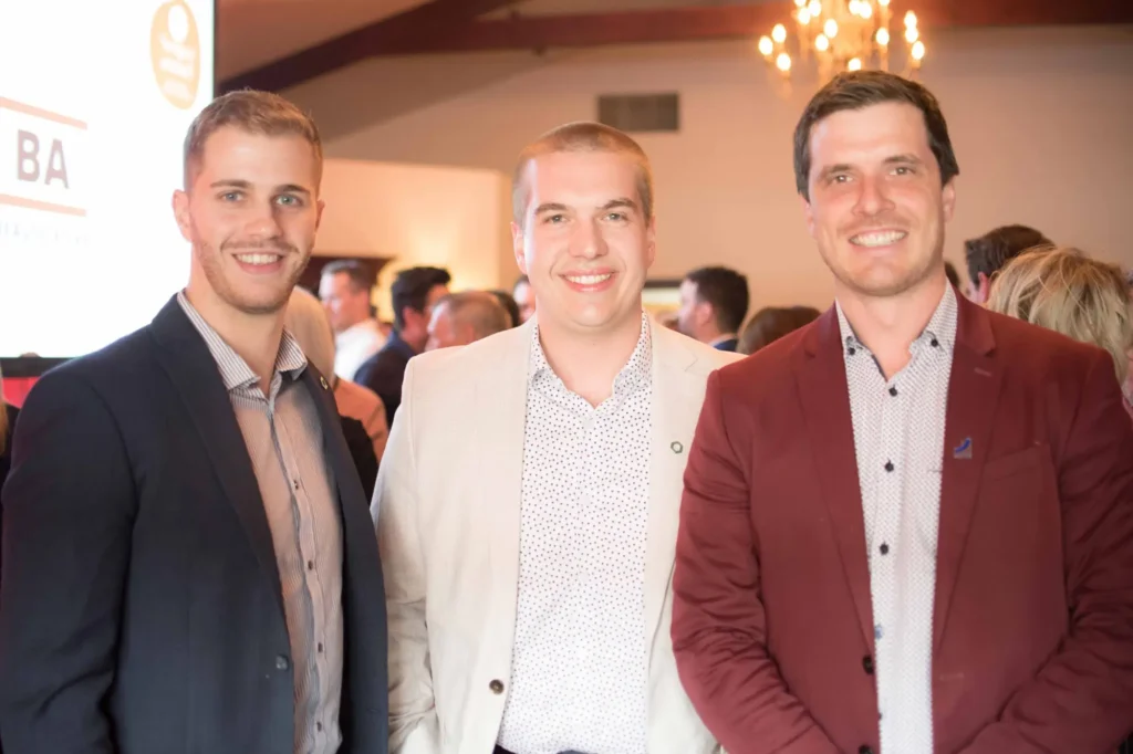 Trois hommes souriants lors d’un événement professionnel
