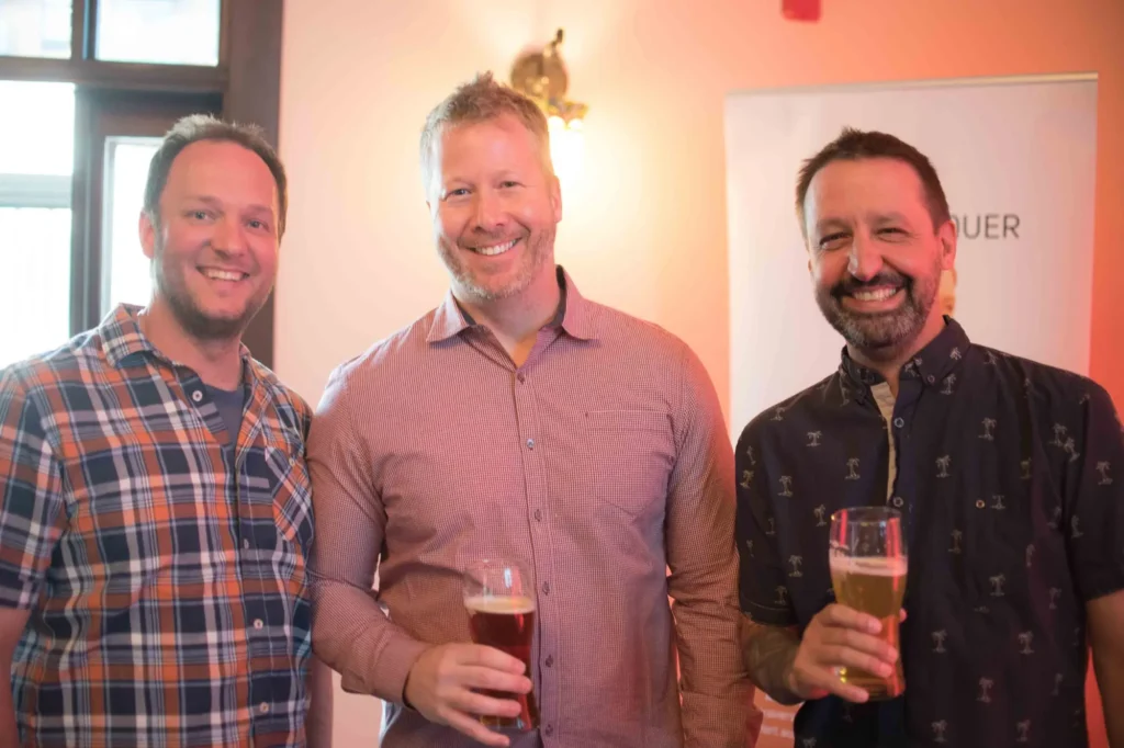 Trois hommes souriants tenant des verres de bière
