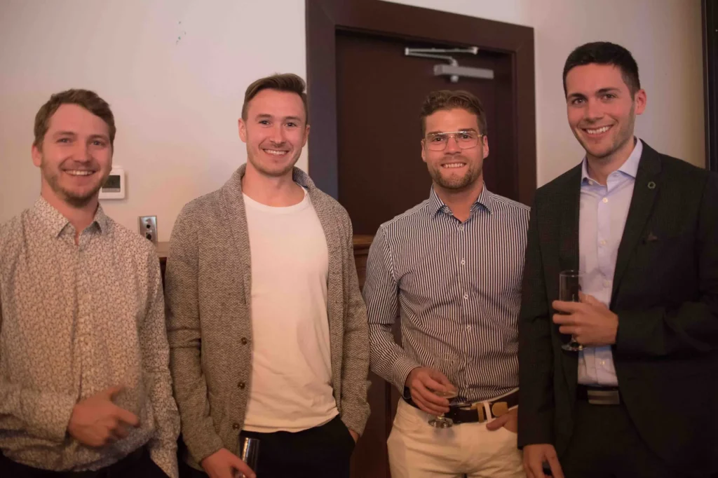 Quatre hommes souriants lors d'une soirée intérieure