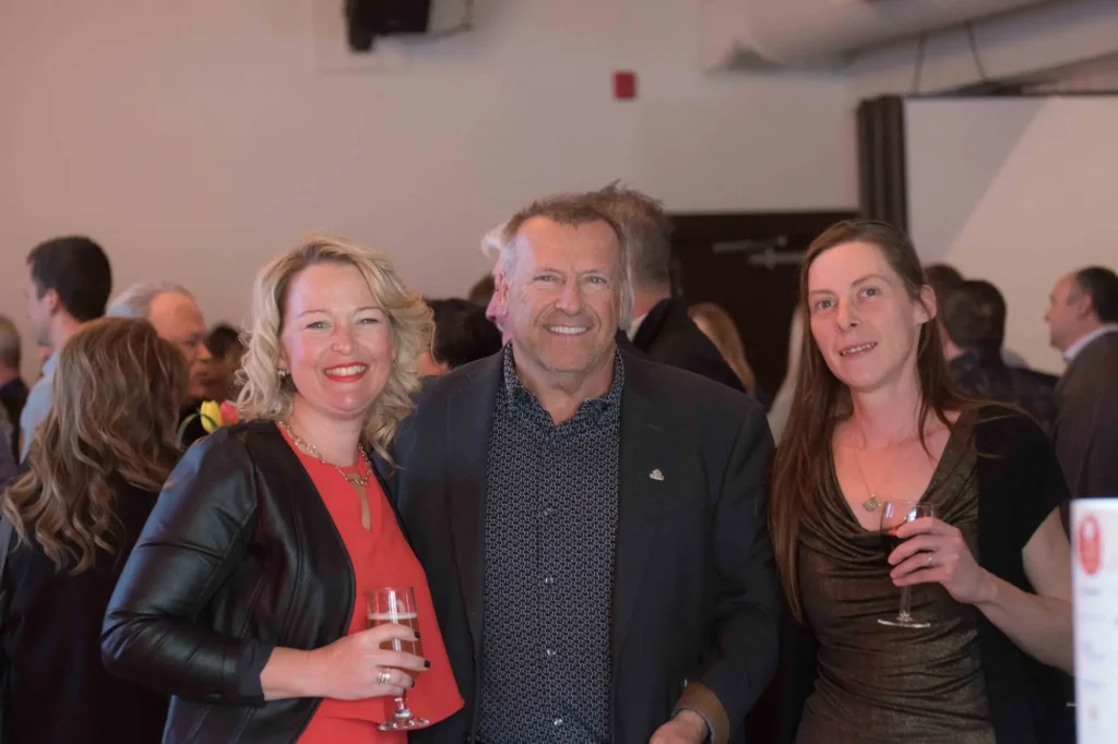 Trois adultes souriants lors d’un cocktail en intérieur