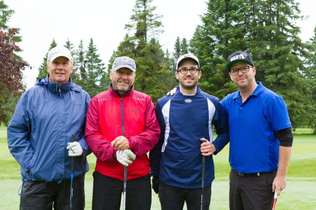 Quatre golfeurs posant sur un parcours verdoyant