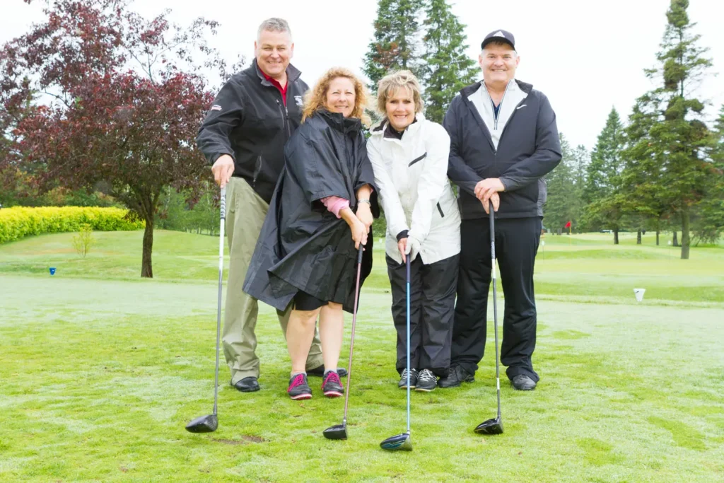 Quatre golfeurs souriants sur un parcours verdoyant