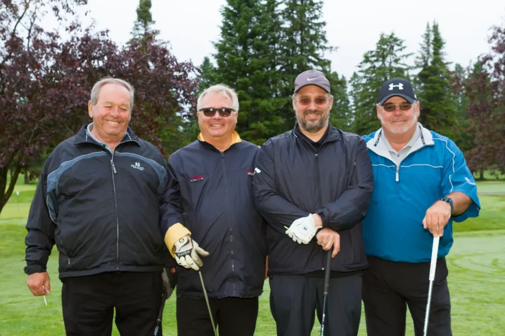 Quatre hommes souriants sur un parcours de golf
