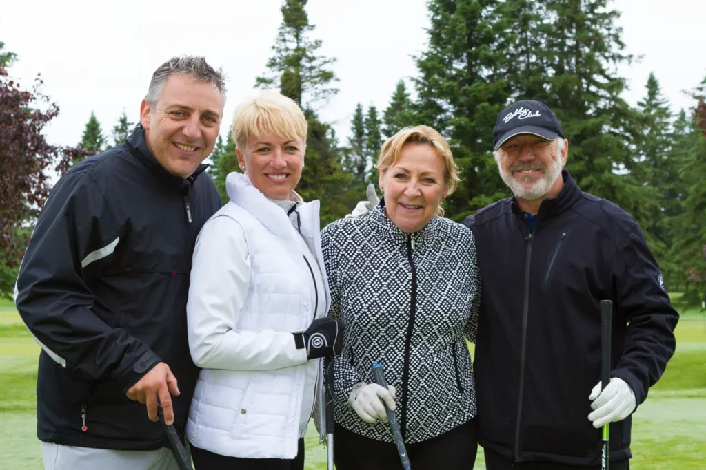 Quatre golfeurs souriants sur un parcours verdoyant