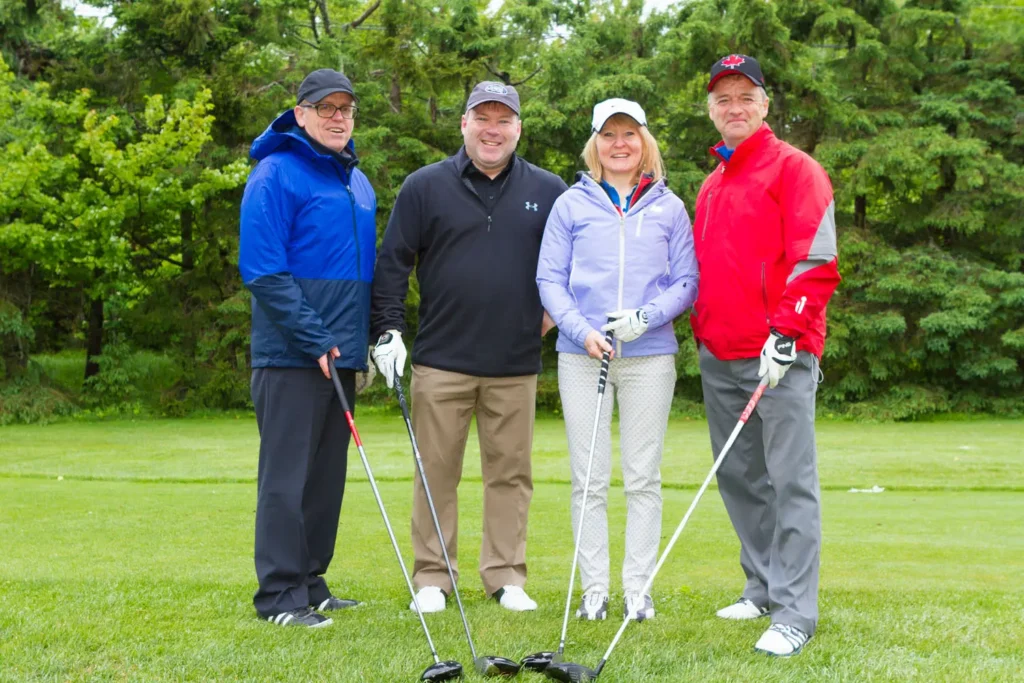 Quatre golfeurs posant sur un parcours verdoyant