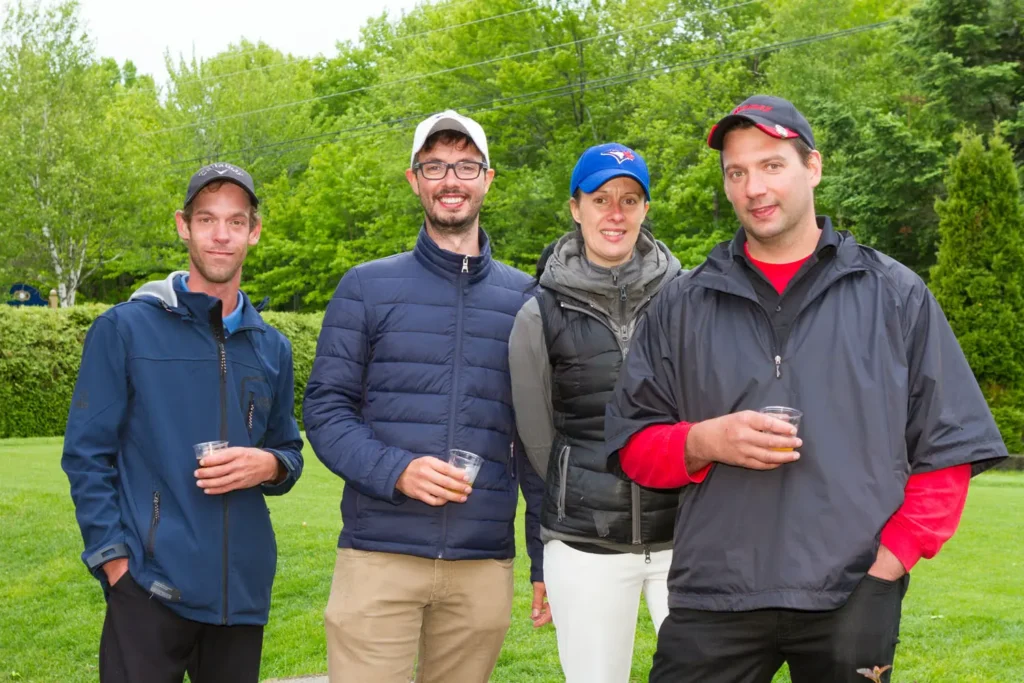 Quatre adultes souriants avec boissons en extérieur