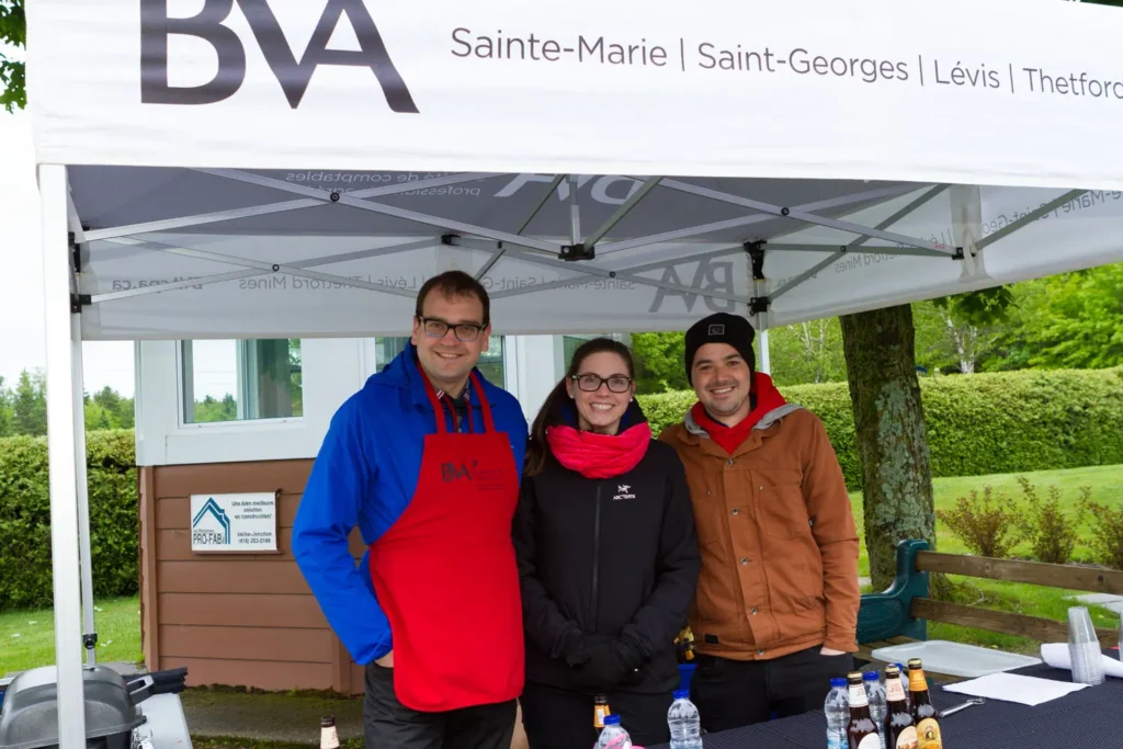 Trois personnes souriantes sous un stand BVA