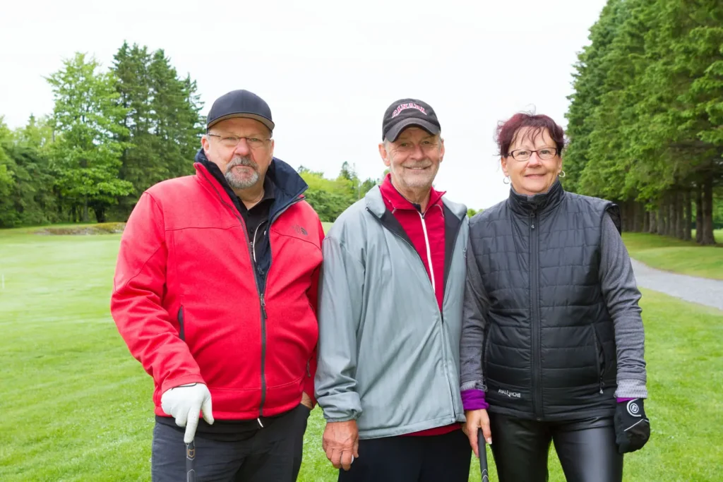 Trois seniors posant sur un parcours de golf