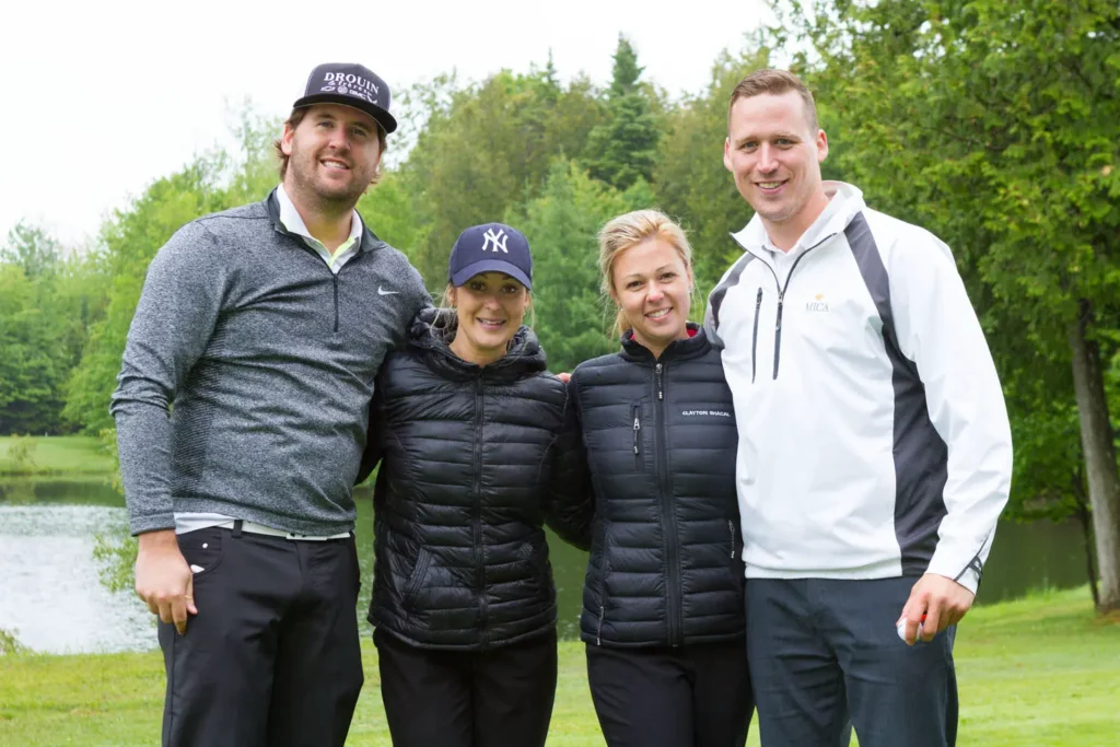 Quatre golfeurs posant près d’un étang verdoyant