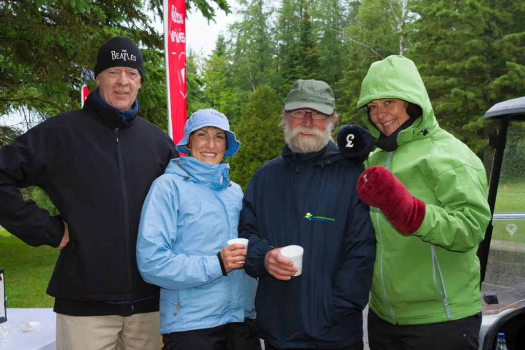 Quatre adultes souriants en extérieur par temps frais