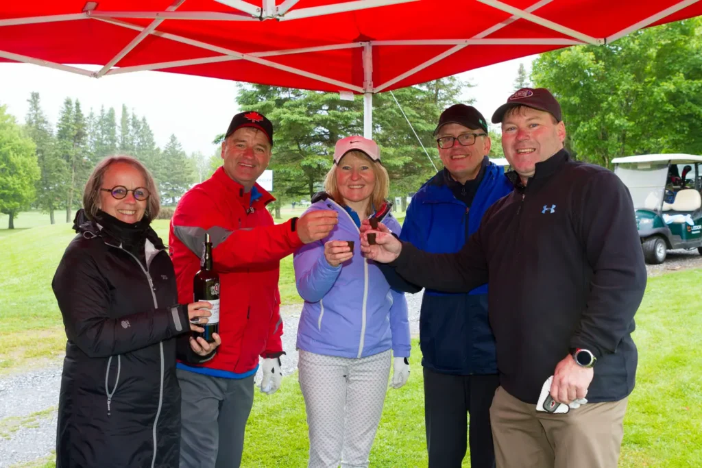Groupe d'amis trinquant sous tente rouge au golf