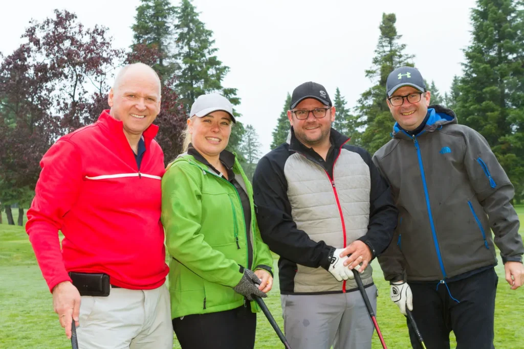 Quatre golfeurs souriants sur un parcours verdoyant