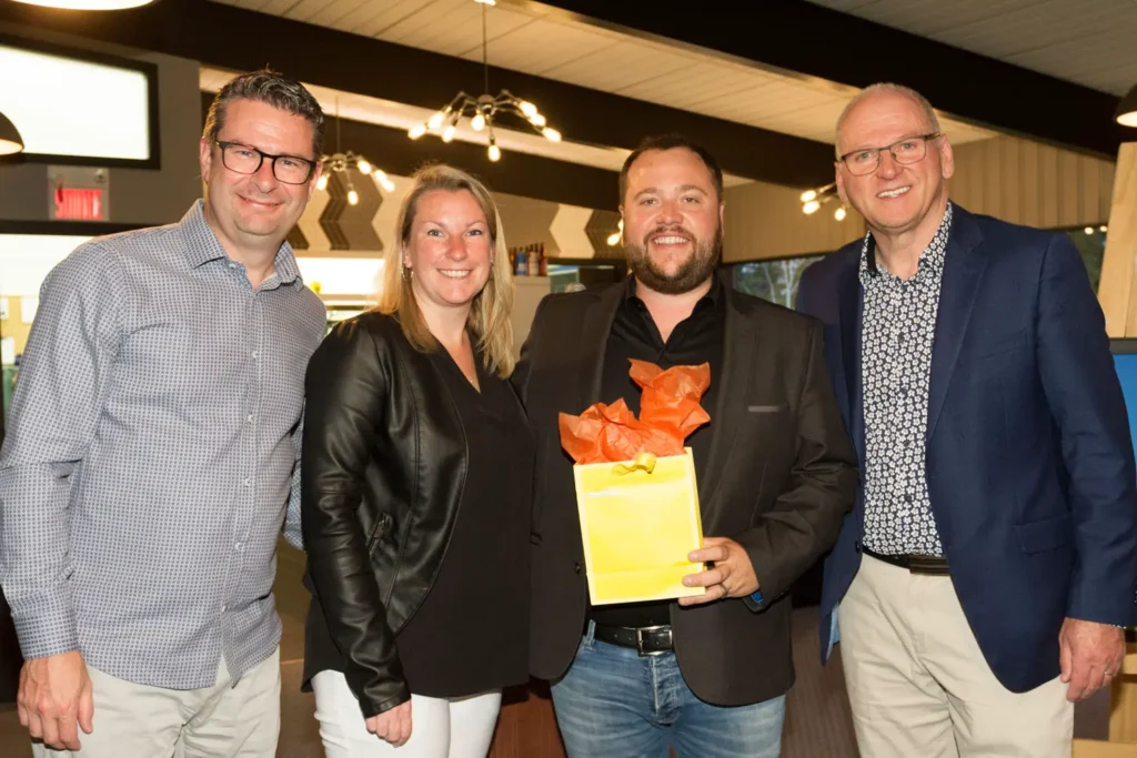 Quatre adultes souriants avec sac cadeau jaune