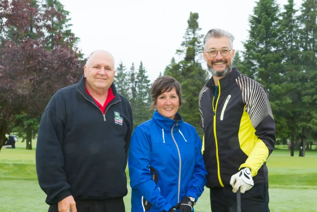 Trois golfeurs souriants sur un parcours verdoyant